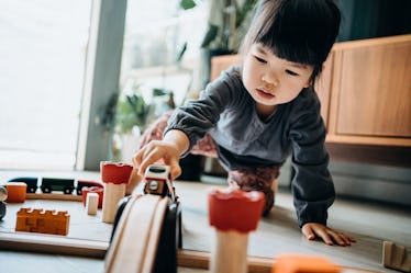 A girl playing with toy trains on the floor.