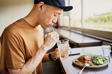 A man drinking from a glass and eating a healthy lunch.