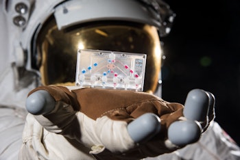 An astronaut holds a chip with human cells.