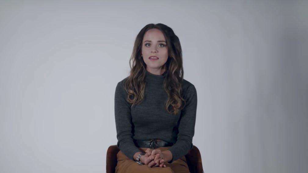 Jinger Duggar Vuolo sits against a white backdrop discussing her new book 'Becoming Free Indeed.'