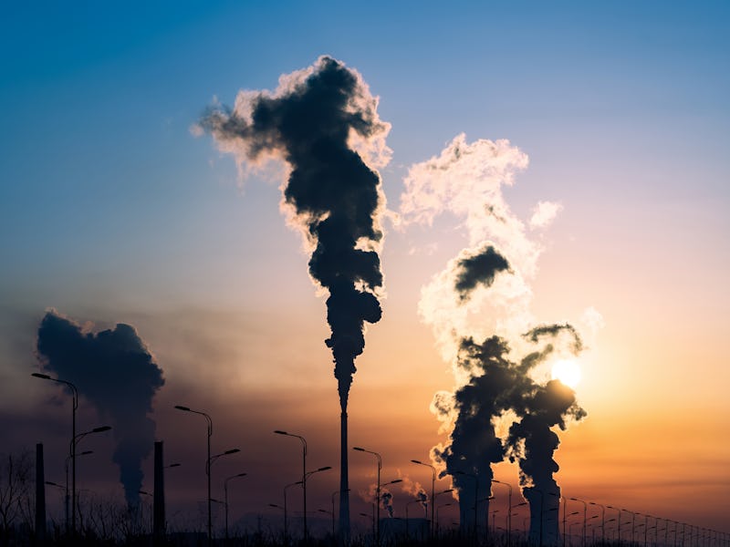 Industrial pipes emitting smoke into the sunset