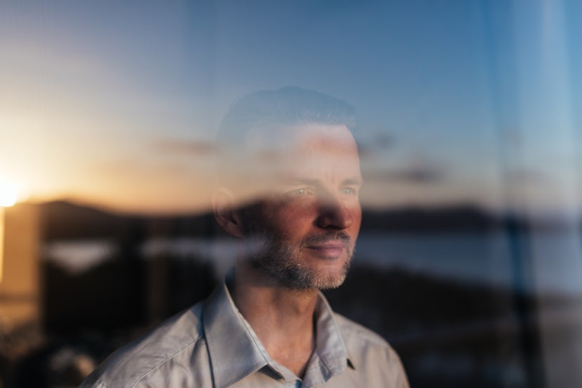 Man looking out large glass window and smiling