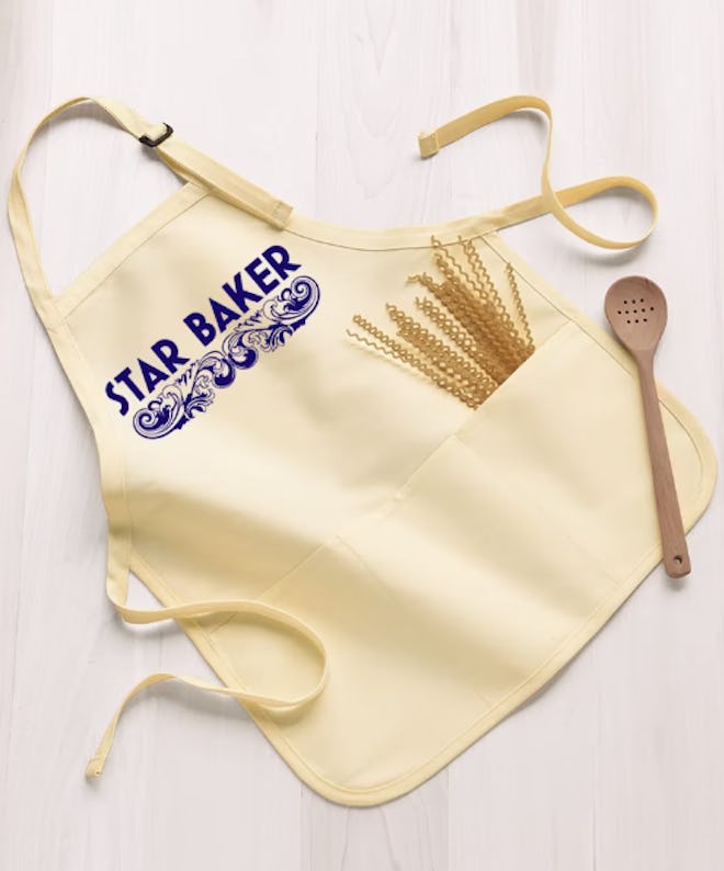 A tan apron that says "Star Baker" in the design of The Great British Baking Show