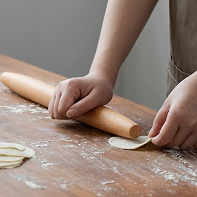 A tapered wooden rolling pin being used to roll out pastry dough