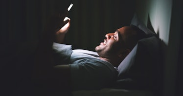 A man texting in the dark in bed.