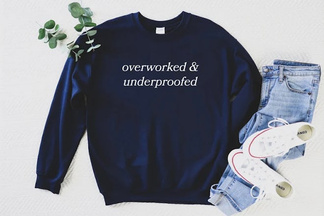 A navy sweatshirt that reads "overworked & underproofed," a funny quote from The Great British Bakin...
