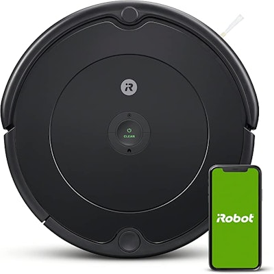Black round robot vacuum with smart phone displaying the accompanying Roomba app