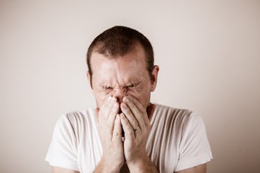 Adult male covering his nose and mouth after sneezing