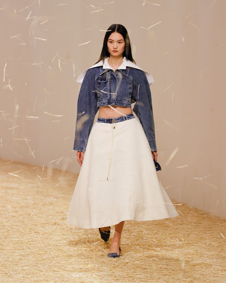 A model wearing a denim jacket top and white dress at Jacquemus spring 2023 runway