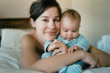 Mother hugging infant while laying in bed. 