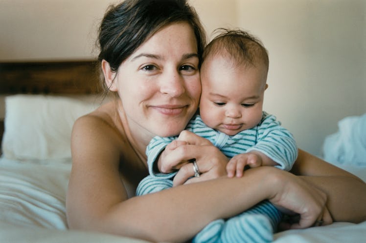 Mother hugging infant while laying in bed.