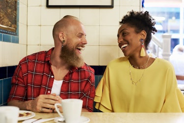 Couple laughing and smiling while sitting beside one another at a diner