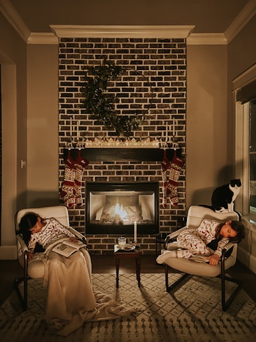 Two little girls asleep in rocking chairs in front of the fireplace, waiting for Santa Claus. Taking...