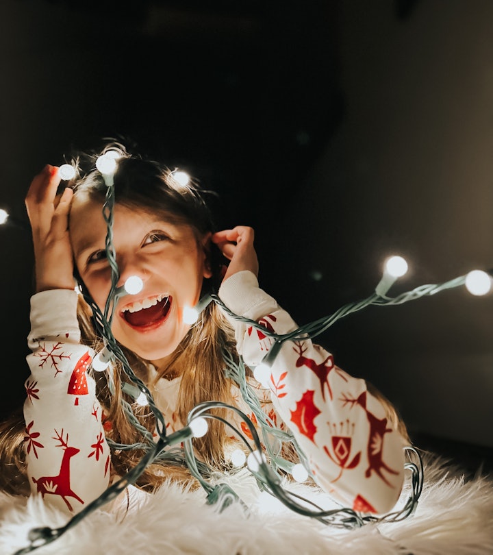 Girl in Christmas pajamas tangled in Christmas lights smiles, in tory about iPhone photography tips ...