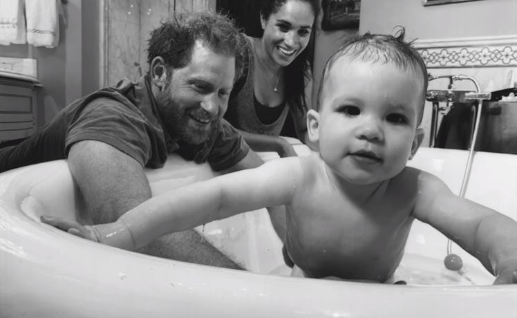 Archie in the bath with his parents behind him.