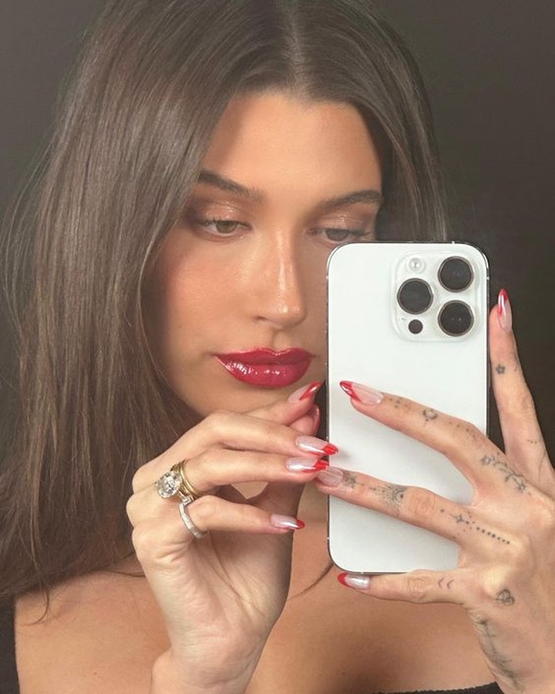 Hailey Bieber wore red French tips on her nails, and matched the manicure with shiny red lipstick. B...