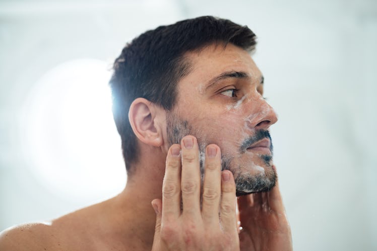 A black-haired man with beard washing his face