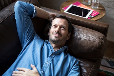 A man laying on the couch with his hand behind his head