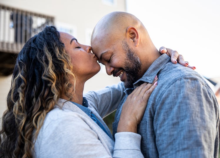 An older man being kissed by a woman on the forehead.