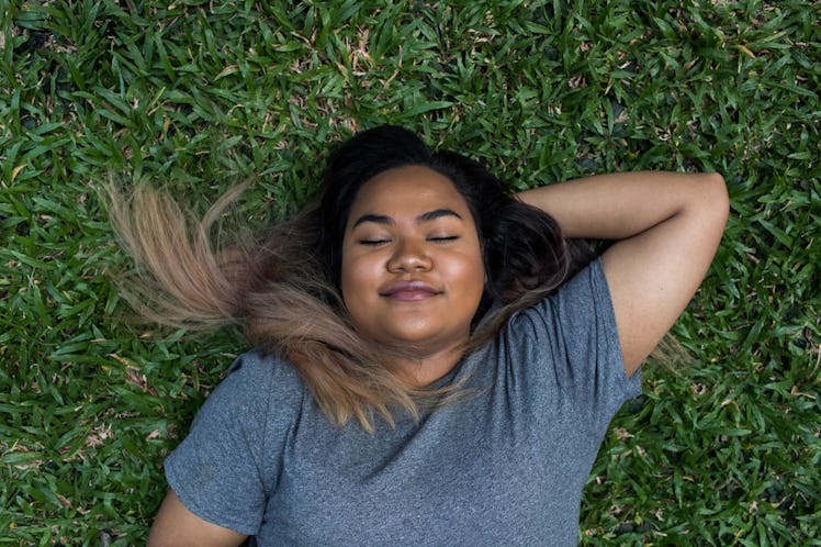 Young woman laying in grass after reading her 2023 yearly horoscope.