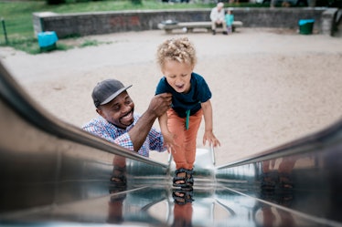 An uncle helping his nephew up a slide.