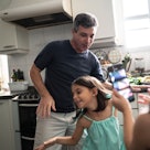 一个白人和他的小女儿在厨房里跳舞。