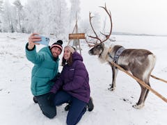 A couple snaps a selfie with a reindeer after booking an Uber Sleigh ride.