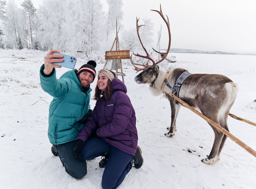 A couple snaps a selfie with a reindeer after booking an Uber Sleigh ride.