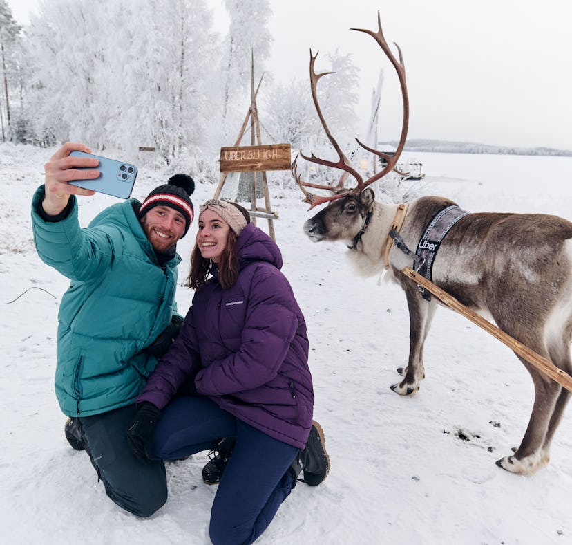 A couple snaps a selfie with a reindeer after booking an Uber Sleigh ride.