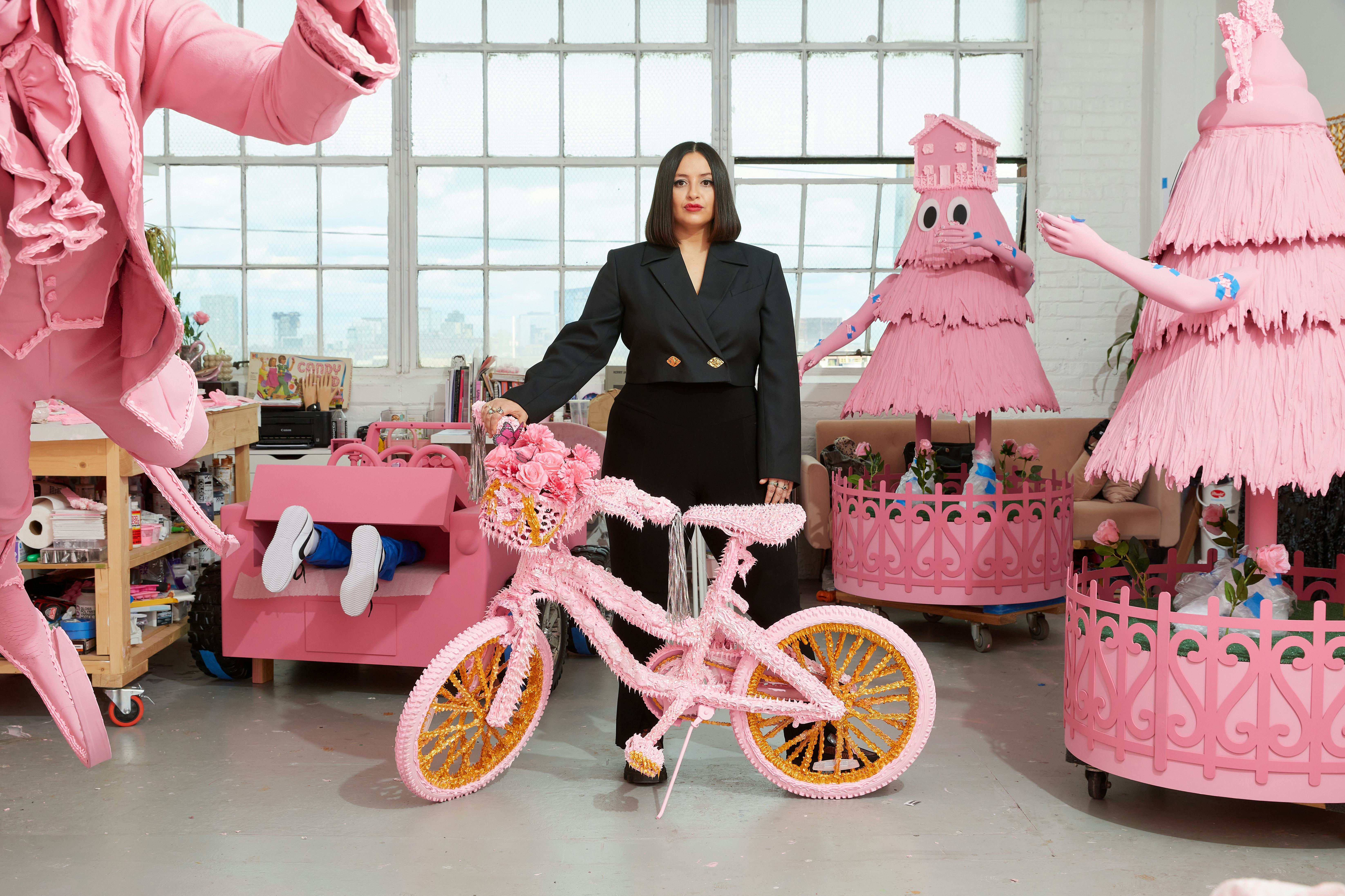 Artist Yvette Mayorga standing amongst her candy-pink creations