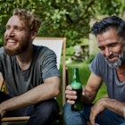 Two men drinking beer in a backyard.