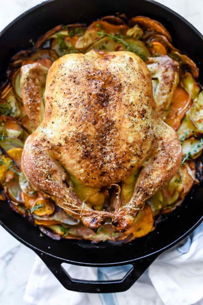 A whole roasted chicken on top of potatoes in a skillet, in a story about one-pot holiday recipes