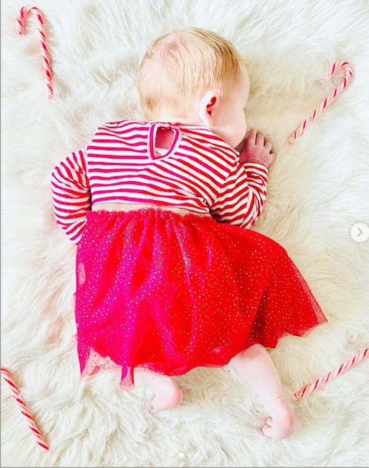 baby lying down on white rug with candy canes for a cute holiday baby announcement 