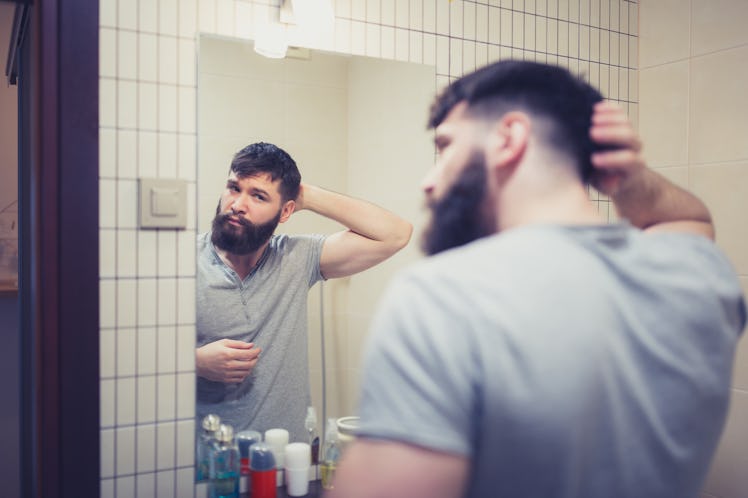 A man looking in a bathroom mirror.
