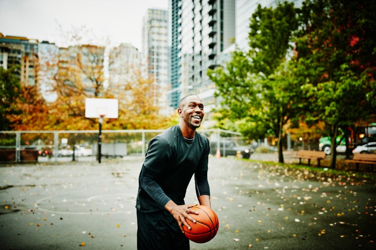 An older man shooting a basketball on an outdoor court.