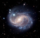 在漆黑的背景下，螺旋星系NGC 6956的蓝色漩涡闪闪发光。