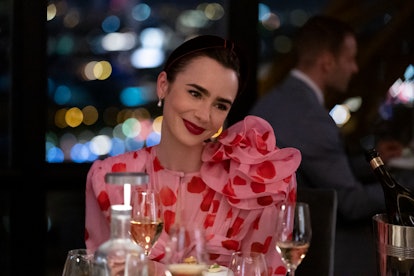 Lily Collins as Emily Cooper in Emily in Paris, wearing a top knot and deep red lipstick. 