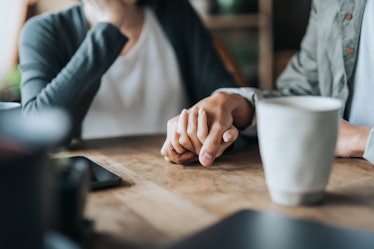 A couple holding hands on a table.