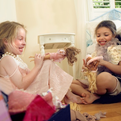 Two girls play with Barbie dolls together.