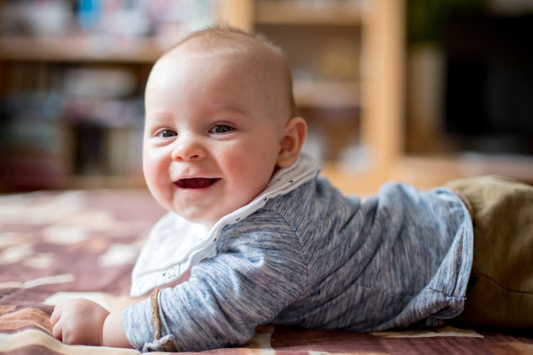 A smiling baby lying on their tummy.