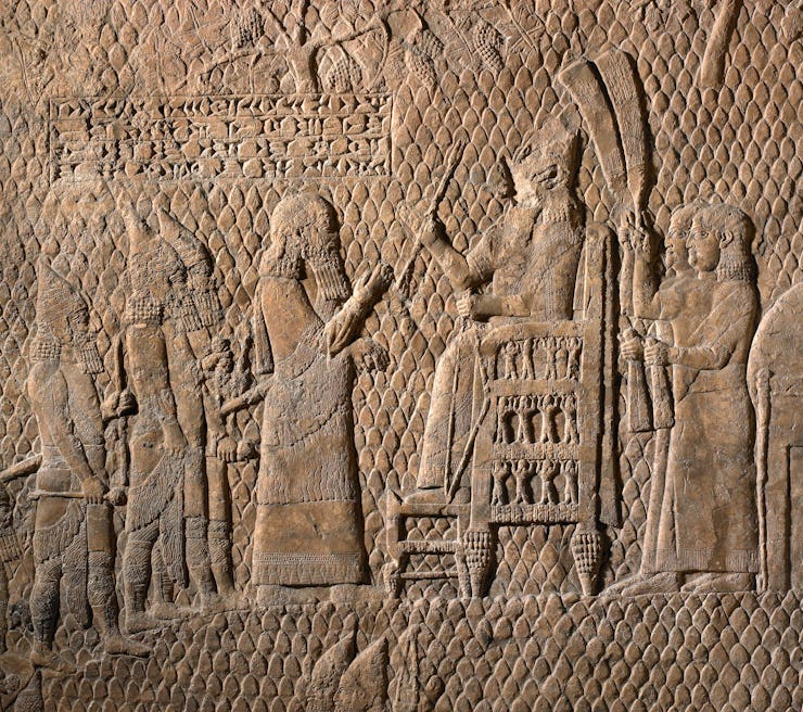 Sennacherib – his face deliberately damaged in antiquity – presides over captives from the Levantine...