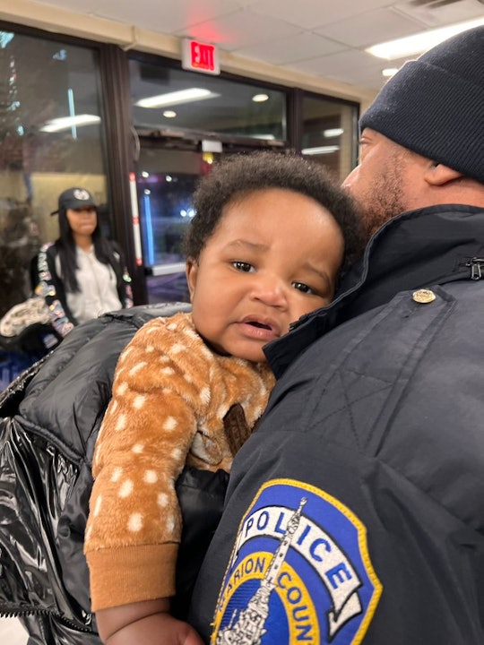 A baby boy looks mildly distressed as he leans against a police officer's shoulder. Kason, the missi...