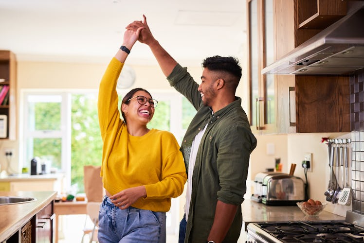 Happy couple smiling and dancing in the kitchen