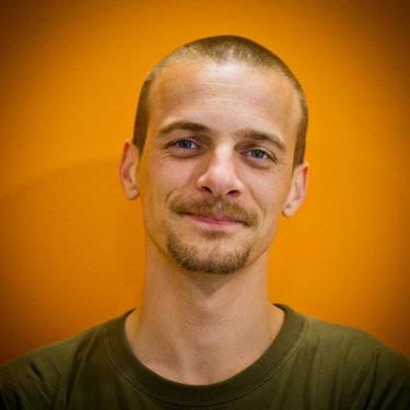 A portrait of David Tisserand with an orange background.