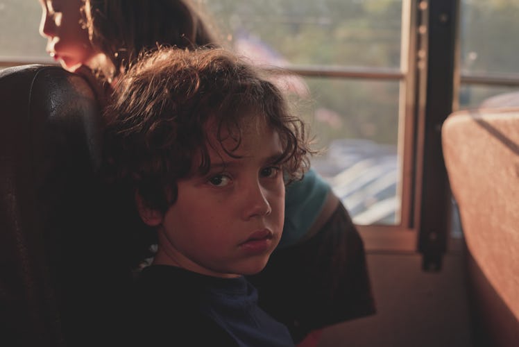 A child on a school bus looking serious.