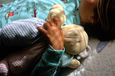 A child sleeping while holding a stuffed animal.