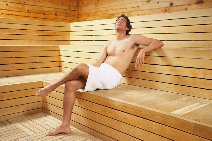 A man with a towel around his waist in a sauna.