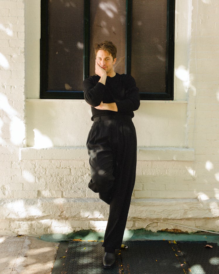 Lucas leans below a window outside of Deux Chats in Williamsburg, Brooklyn