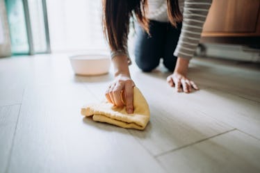 A woman on the ground scrubbing the floor with a rag.