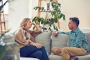 Middle aged man and woman sitting on the couch talking